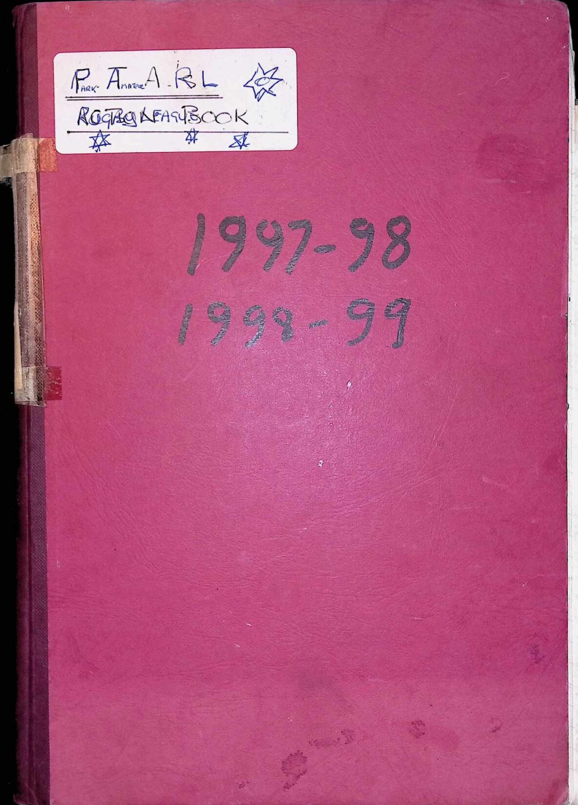Scan of a red leather-look book cover with a white sticker on the top left and black marker pen dates "1997-98 1998-99" written in the middle