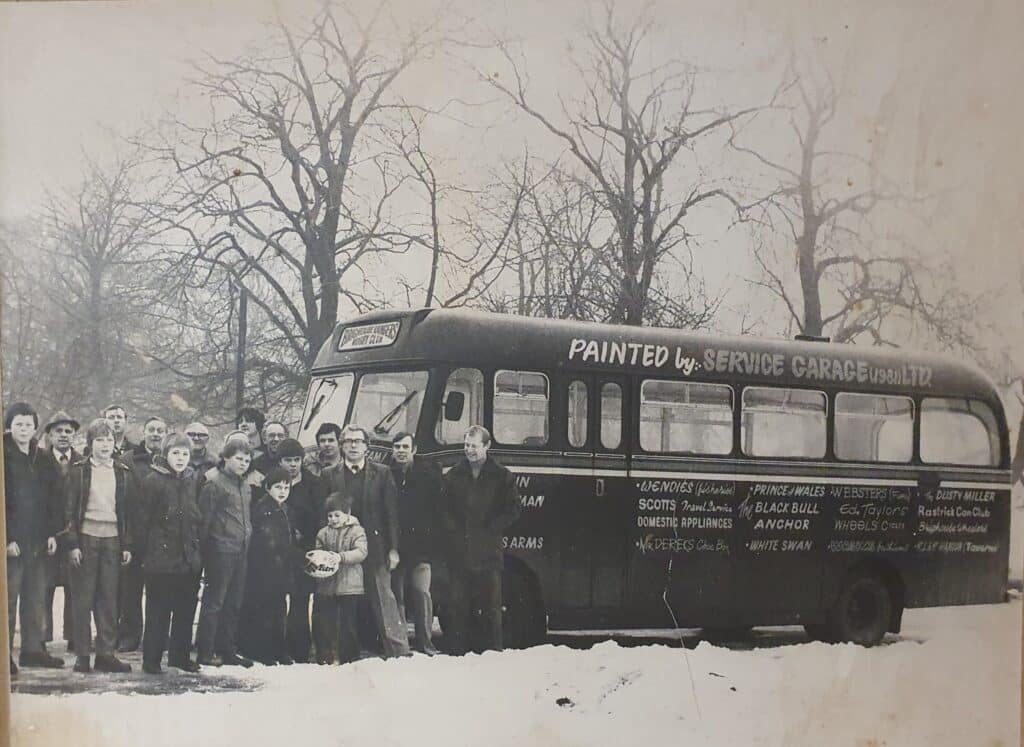 black and white photo of people stood at the front of a bus in the snow