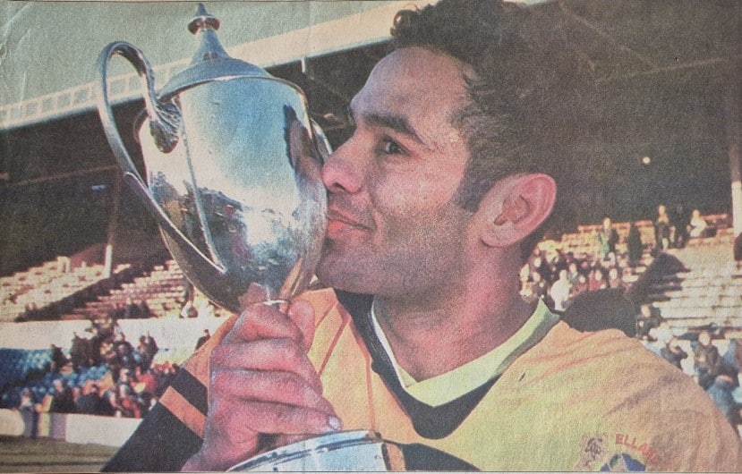 person holding an award cup kissing it and looking very happy