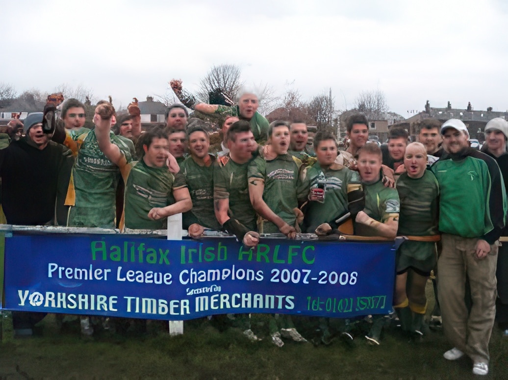photo of a group of players in green uniforms celebrating and holding a blue banner 