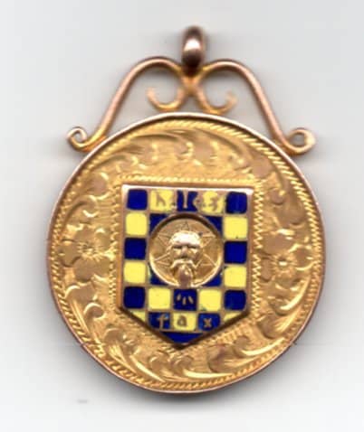photo of a round gold medal with checkerboard detail in the middle