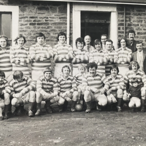 black and white photo of a team wearing their stripey kits, standing in front of a building