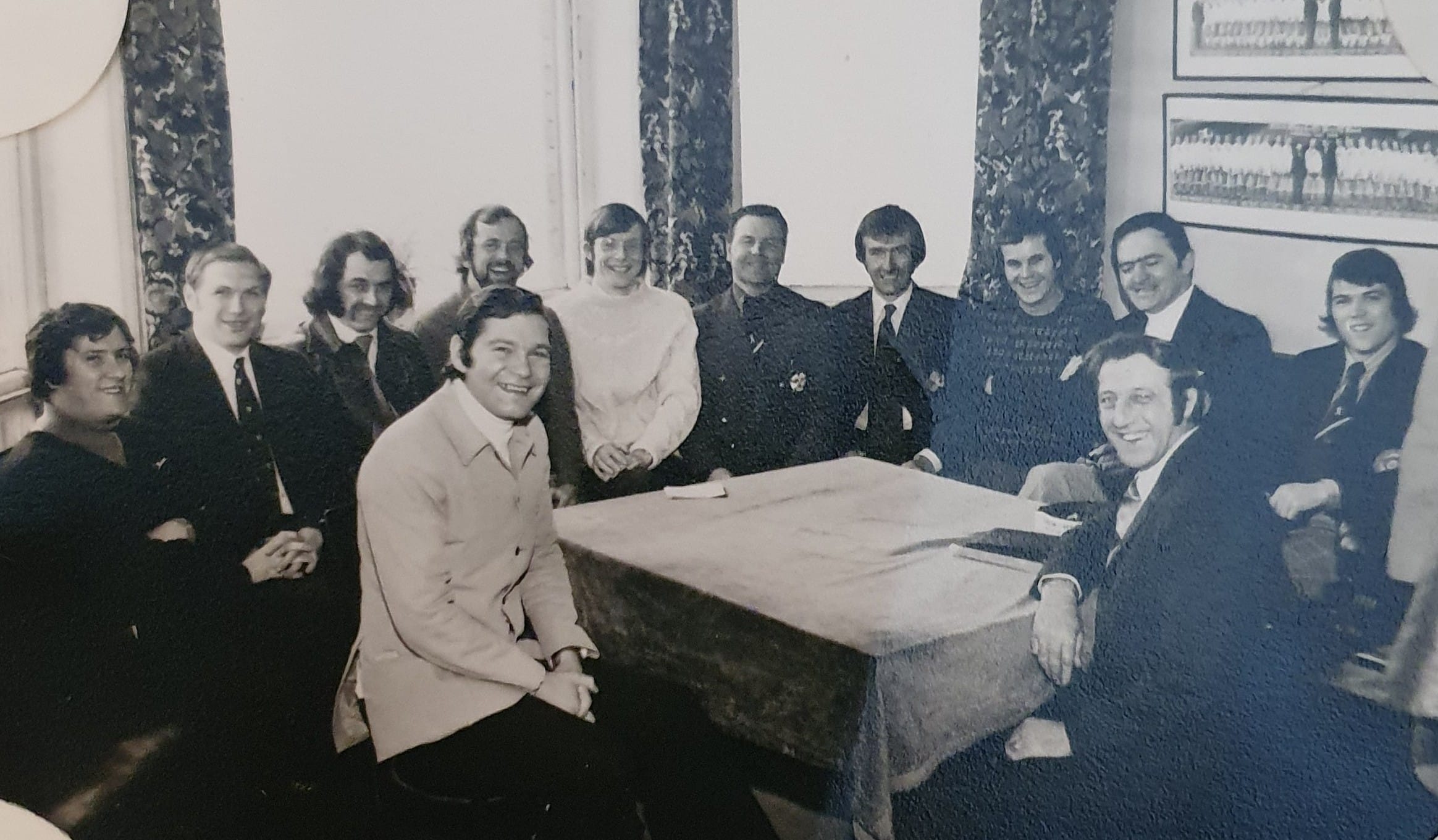 black and white photo of people sat around a table smiling 