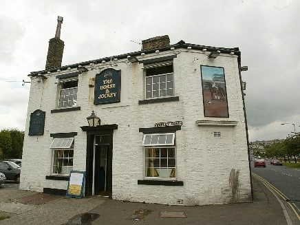 colour photo of the front exterior of the Horse and Jockey pub, which is cream with four sash windows