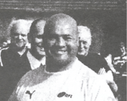 black and white photo of Mark Sutcliffe, who is smiling and wearing a sports top