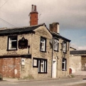 old colour photo of a the side of a building with black window surroundings and two chimney breasts