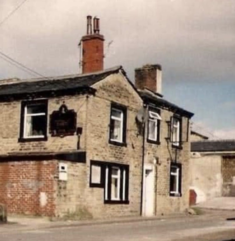 old colour photo of a the side of a building with black window surroundings and two chimney breasts