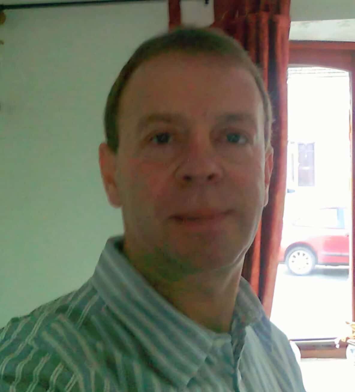 colour selfie photo of Nick Oddy, who has short hair and is smiling, wearing a stripey shirt