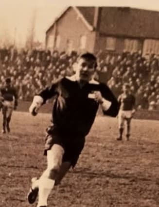 old sepia photo of a person wearing a kit running on a pitch