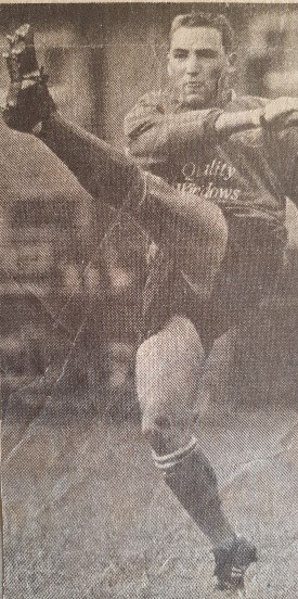 black and white photo of a player kicking their leg up high mid-game