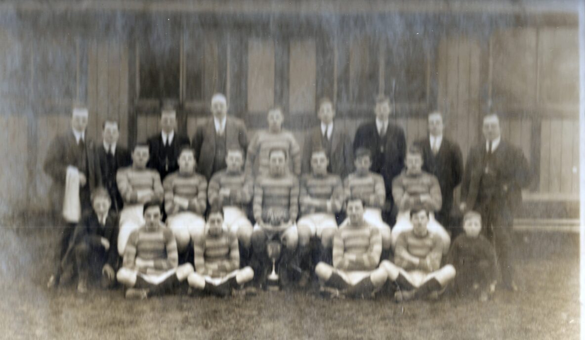 black and white photo of Siddal team, in three rows, the front two rows are wearing stripey kits and the back row are standing and wearing smarter attire