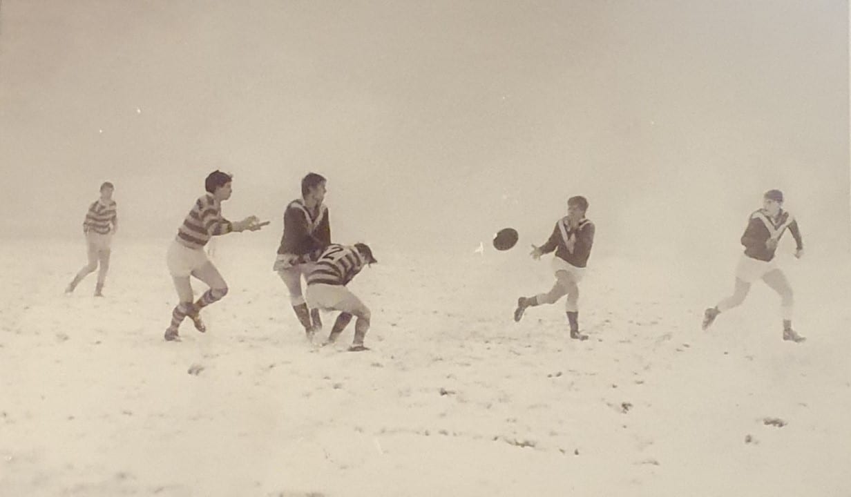 black and white photo of of a game in the snow, with players passing the ball 