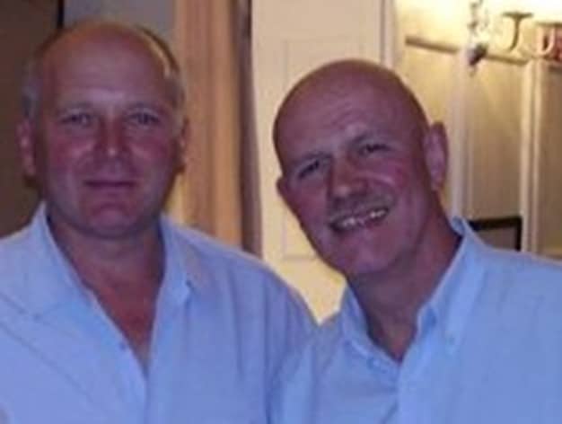 colour photo of Paul Shaw and Billy White who are both bald and smiling for the camera, wearing light-coloured shirts