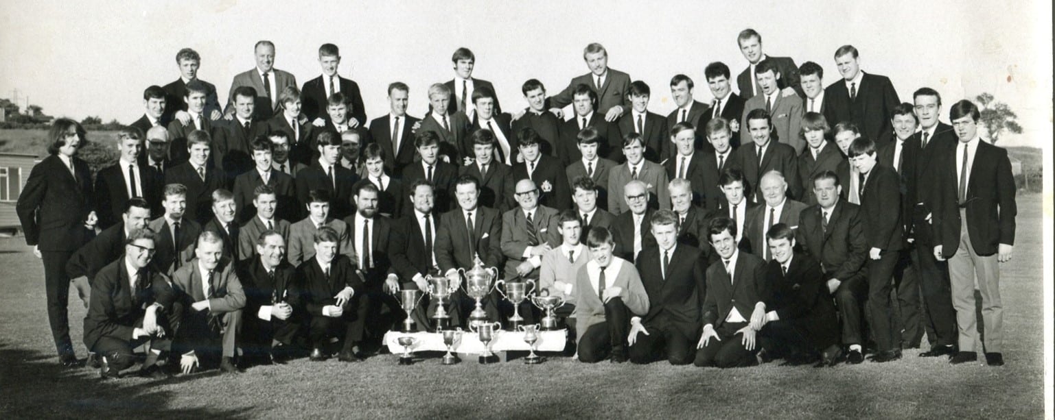 black and white photo of Halifax Championship Trophy win in 1969, rows of people wearing suits with around five trophy cups sitting in the front 