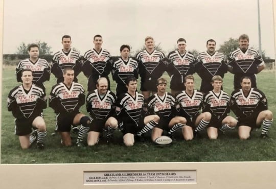 colour photo of Greetland team 1997-8, players are wearing their kits and positioned in two rows on a field, with printed names below the photo