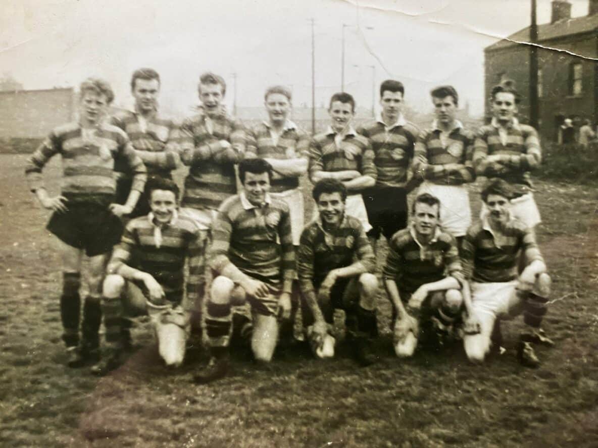 black and white team photo of Queens Road team in 1959, they are in two rows wearing their stripey kits and on the pitch