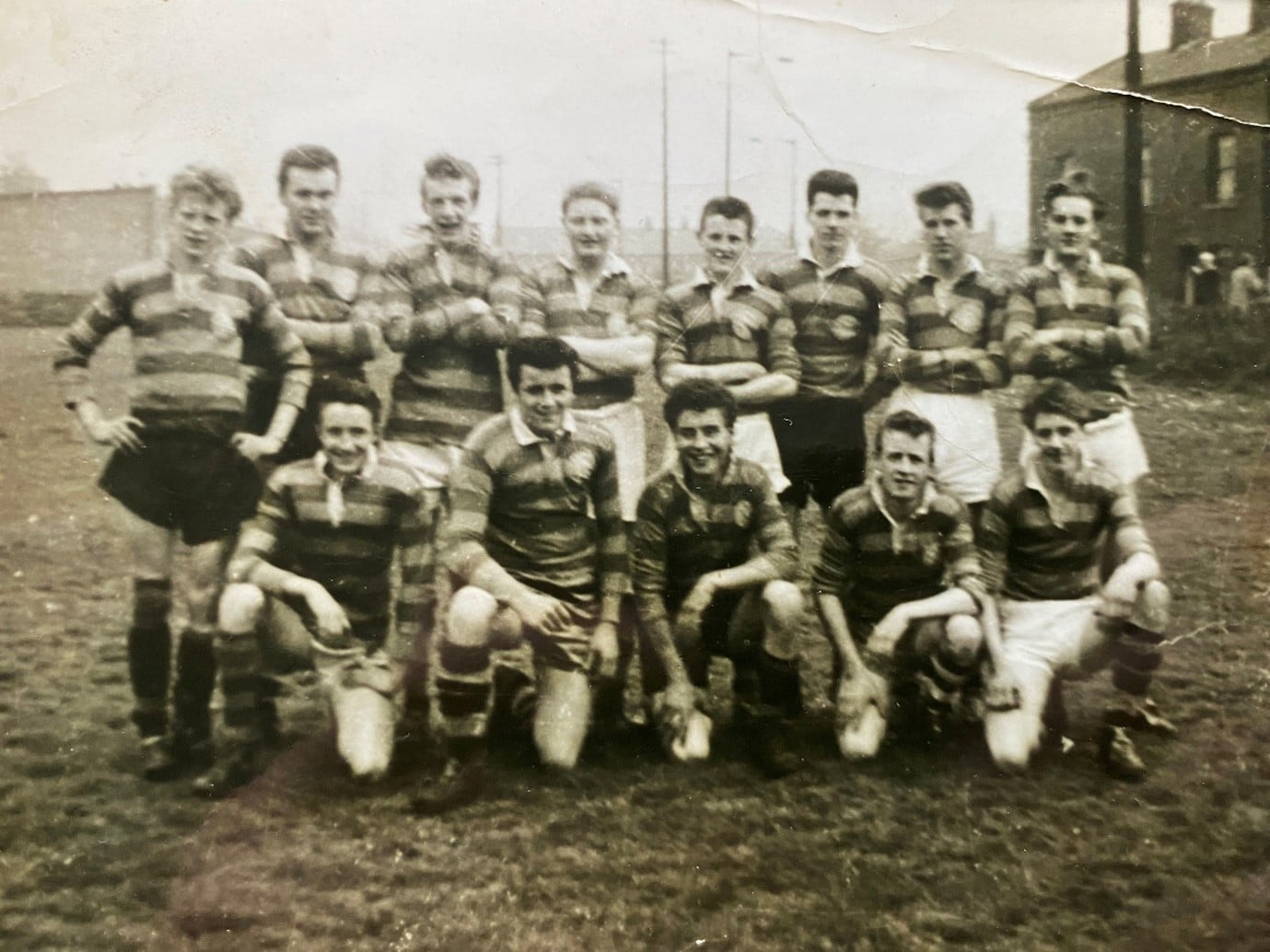 black and white team photo of Queens Road team in 1959, they are in two rows wearing their stripey kits and on the pitch