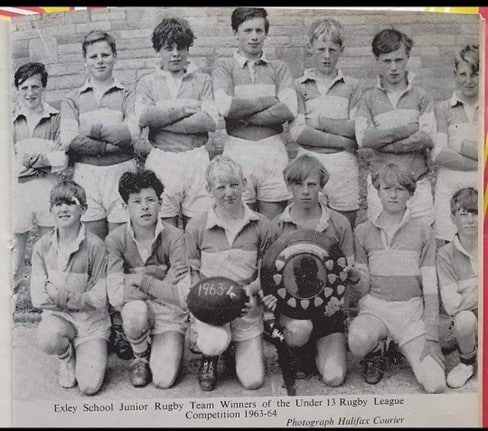 black and white photo of the 1963-4 under 13 competition winners, in two rows, wearing their kits and standing on grass, the front two players are holding a ball and a trophy plate 